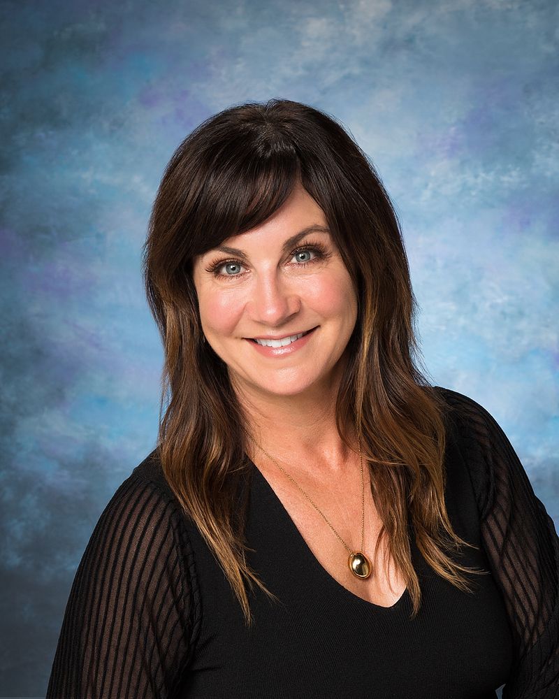 Business headshot of a woman on a painted blue backdrop