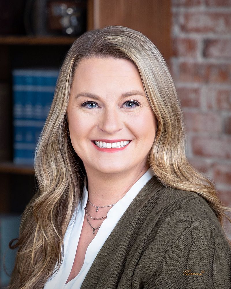 Business headshot of a woman in an office with bookshelves and a brick wall