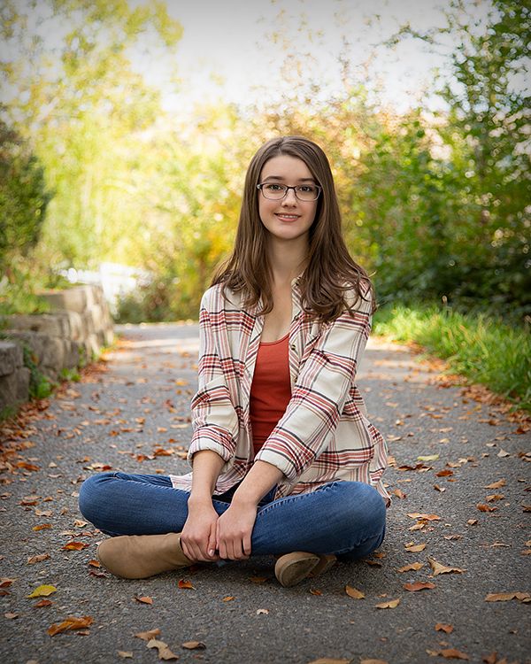 Senior sitting cross-legged on a leaf-covered path