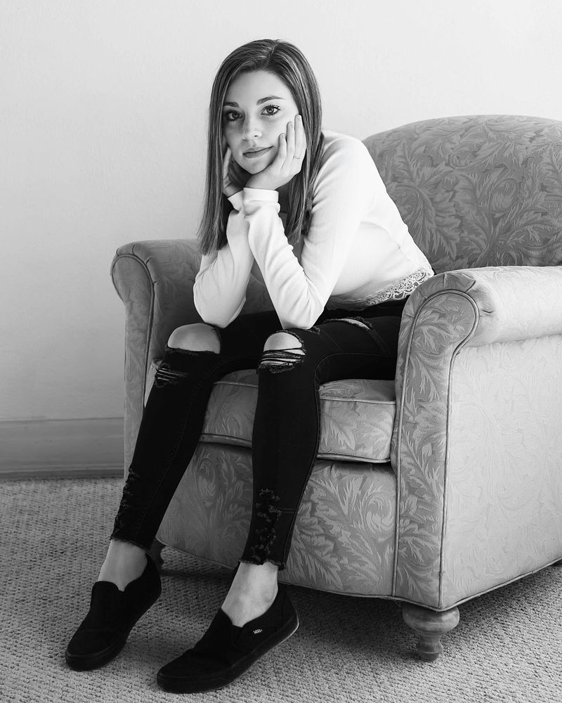 Black-and-white portrait of a senior curled up in an armchair
