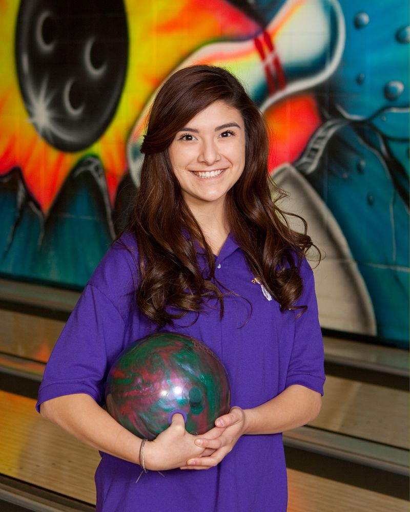 Bowler holding a bowling ball in front of a painted mural