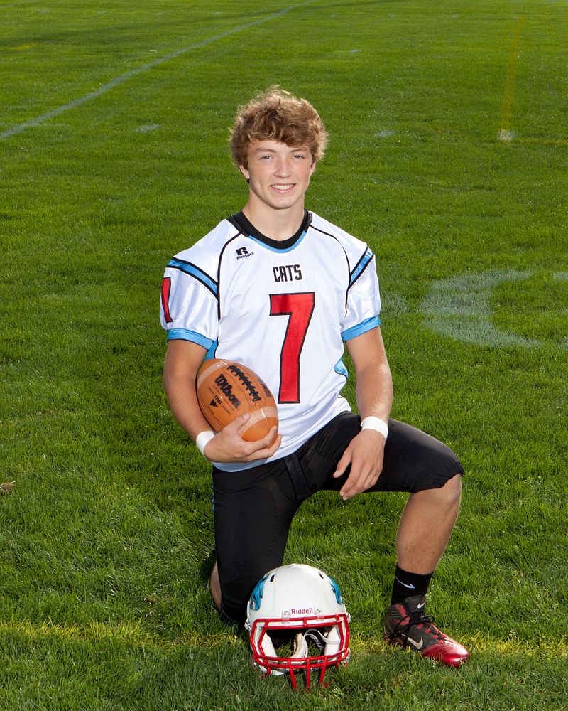 Football player kneeling on the field with a ball and helmet