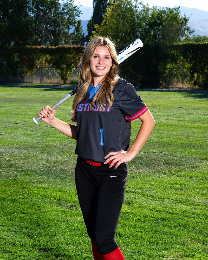 Softball player resting a bat on her shoulder on the field
