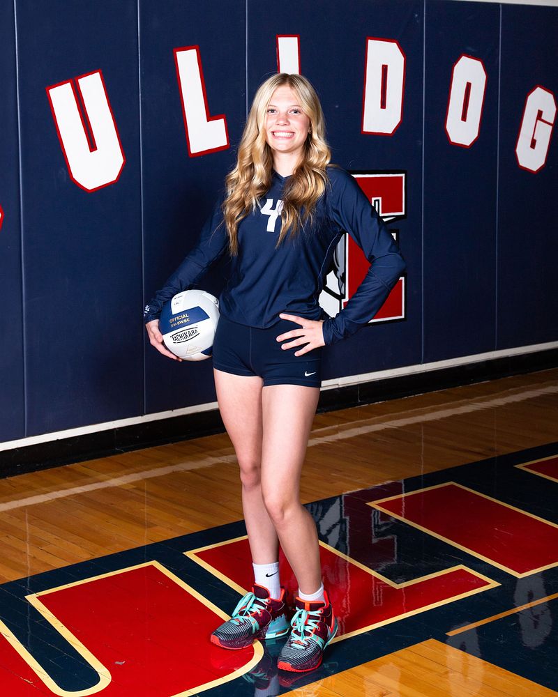 Volleyball player standing on the gym floor with a ball