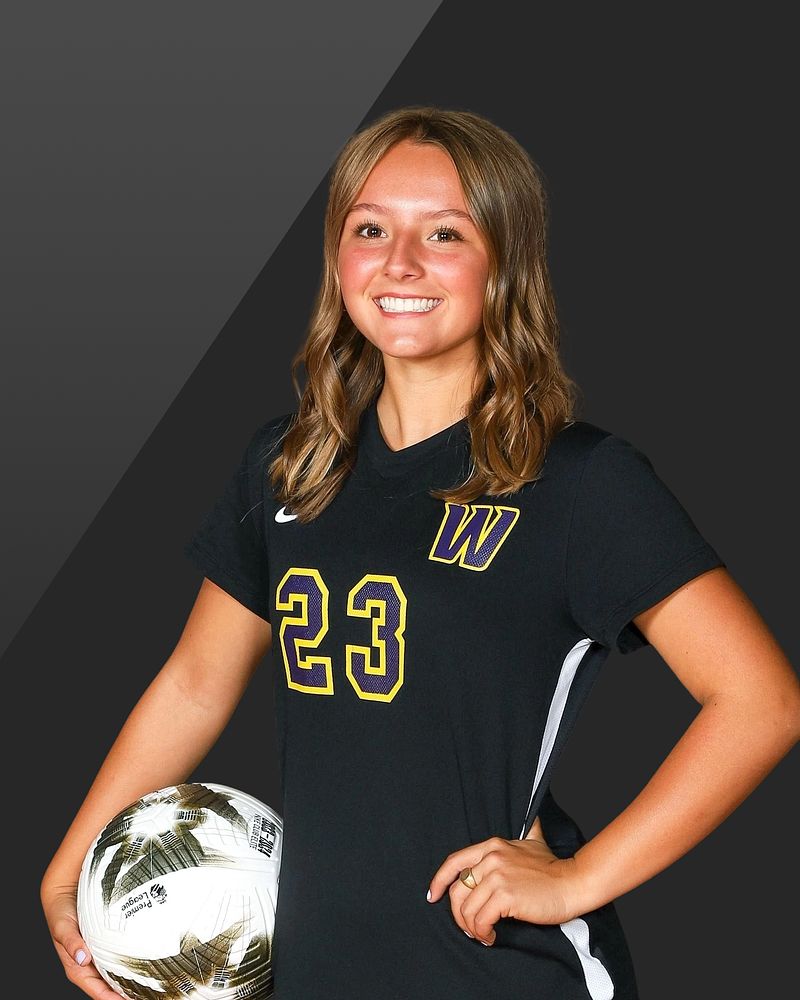 Soccer player holding a ball against a dark studio background